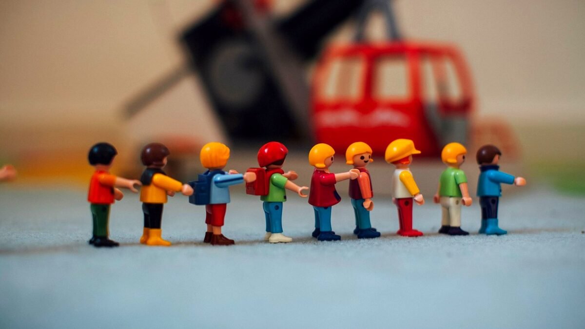 Small plastic toy figures standing in a row next to a toy helicopter