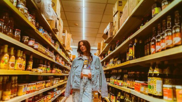 A shopper walks a grocery aisle and looks at products on the shelf.