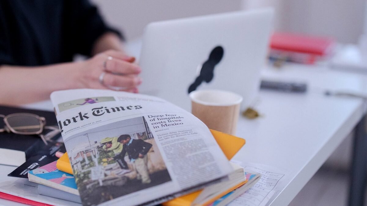 Stylized desk with newspaper, books, and coffee in a modern workspace setting.