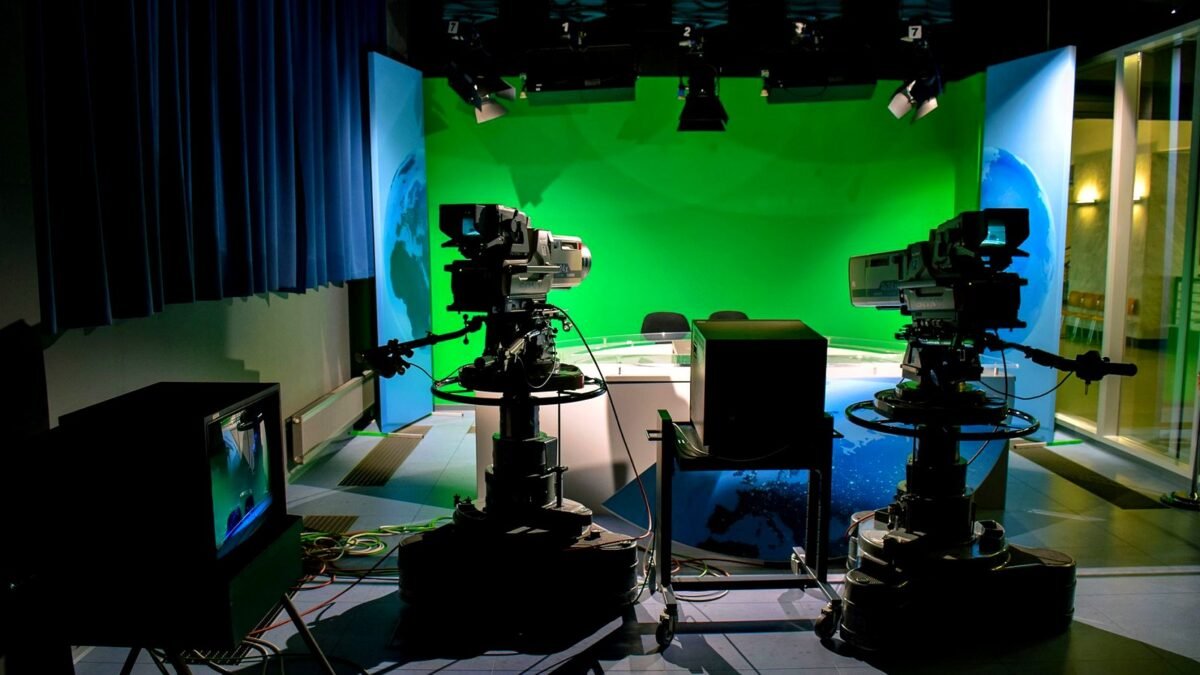 A TV studio setup featuring cameras and a green screen for production purposes.