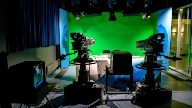 A TV studio setup featuring cameras and a green screen for production purposes.