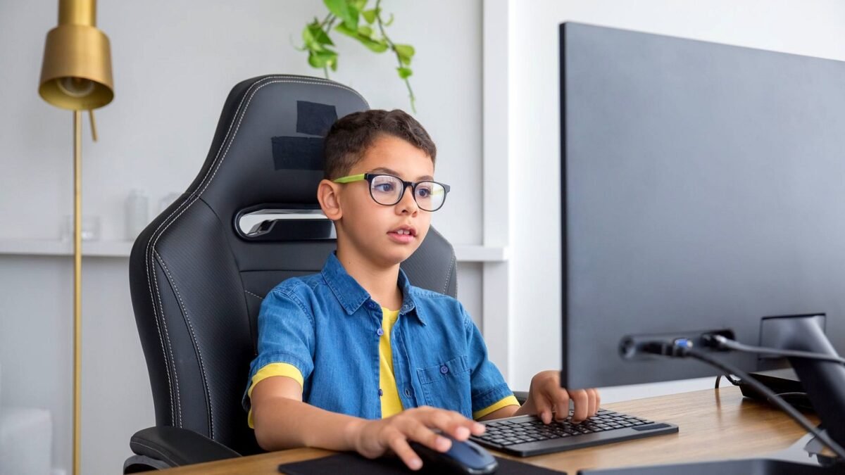 Young person at a desktop computer in a bright home office, building a game