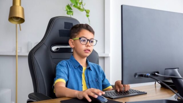 Young person at a desktop computer in a bright home office, building a game