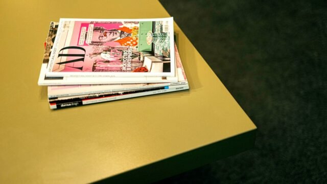 A neat stack of colourful printed magazines on a light table
