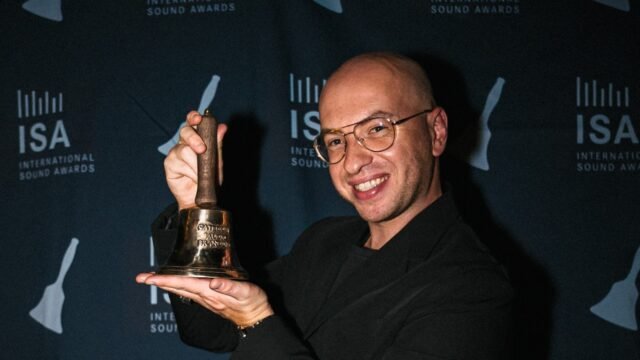 Rafał Konieczny holding the International Sound Awards 2026 trophy at the awards backdrop