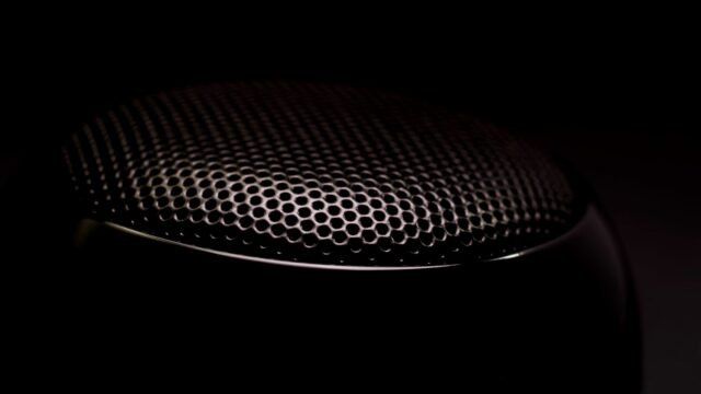 Close-up of a black speaker grille, showing the fabric mesh and rounded edge of the cabinet.