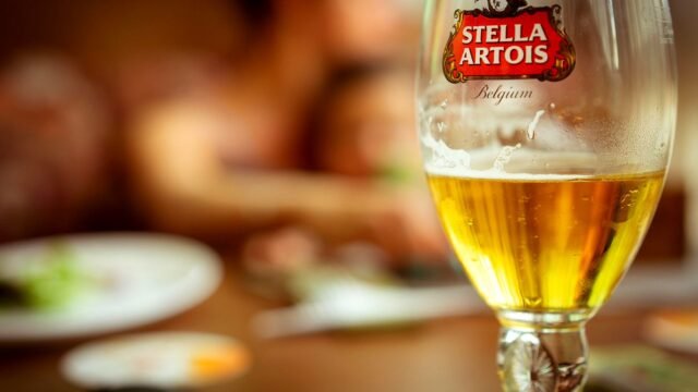 A glass of Stella Artois lager on a table in a pub, with the brand logo on the glass