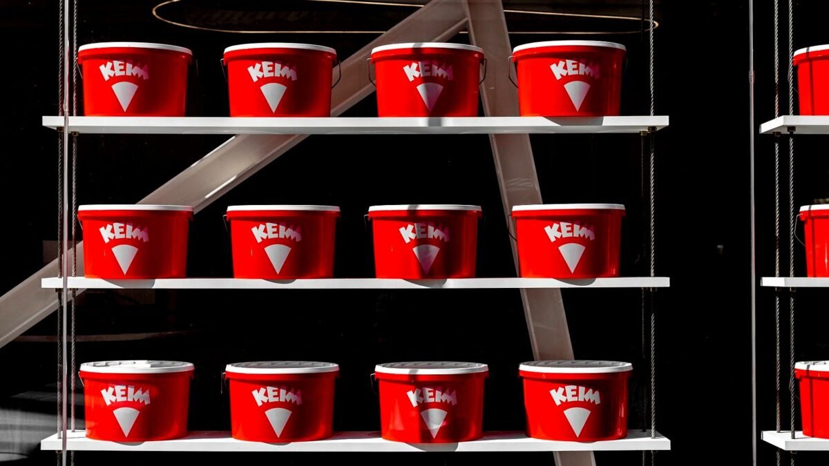 Red paint tins stacked on shelves in a home improvement store aisle