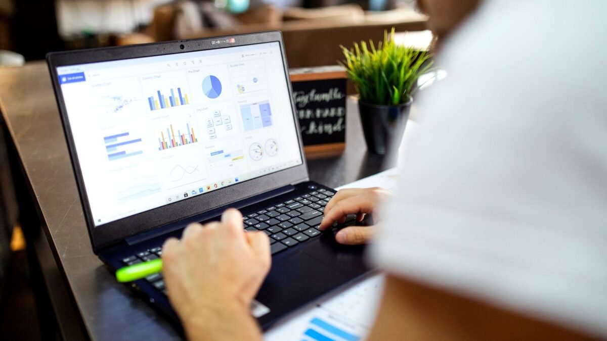 Laptop screen with charts next to printed tables during a media budget review