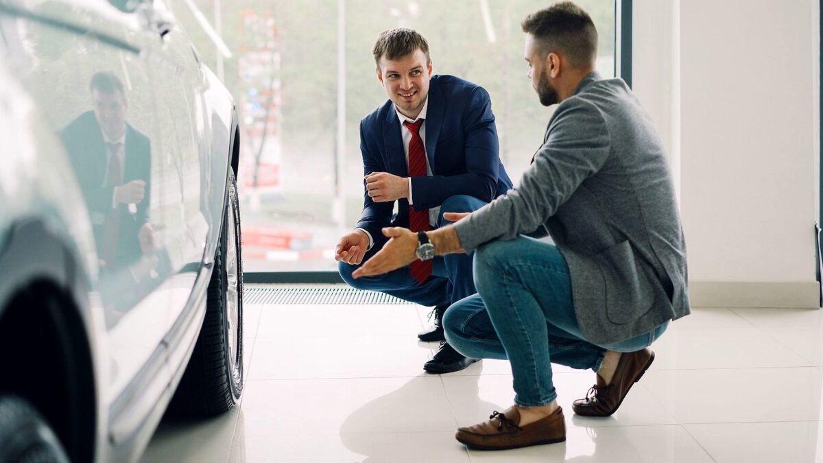 Two people discuss a car inside a modern showroom.