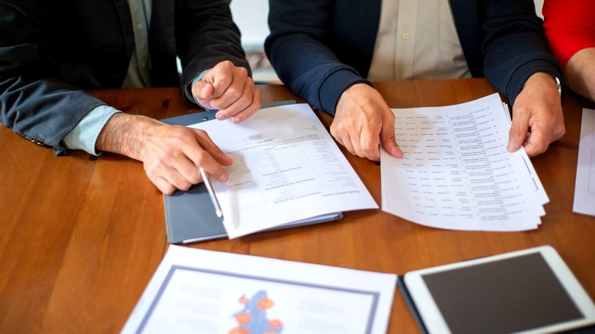 Two people at a desk going through printed documents in an office