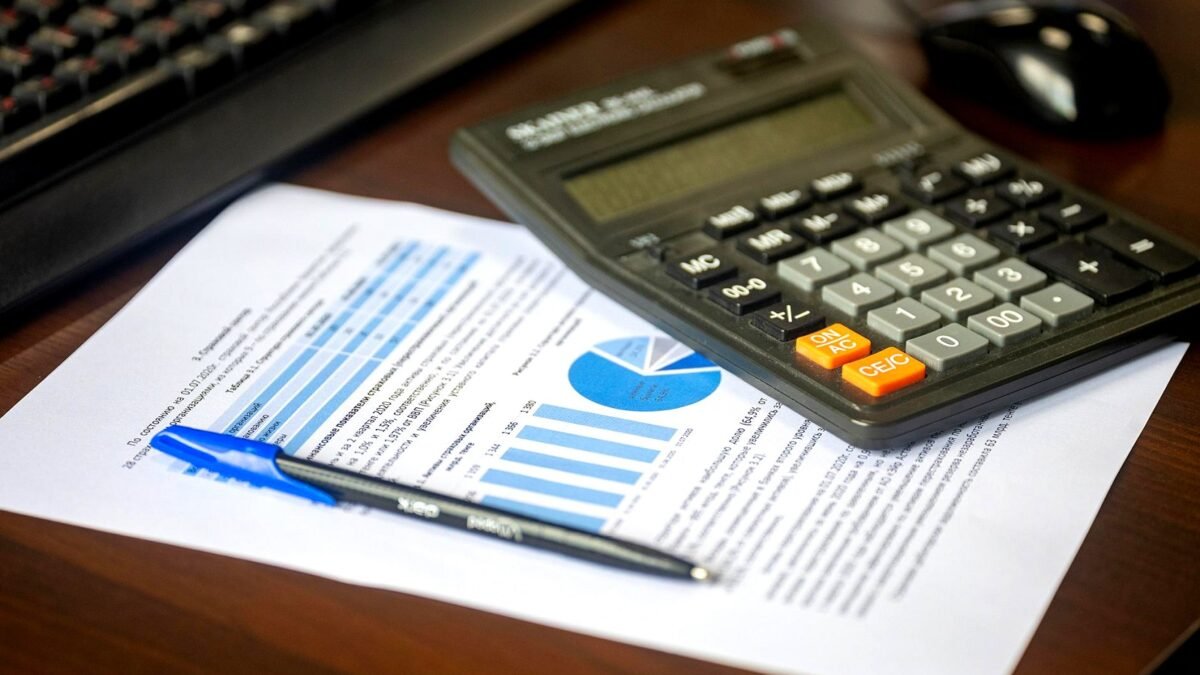 A calculator, a pen and a printed financial report laid out on a desk