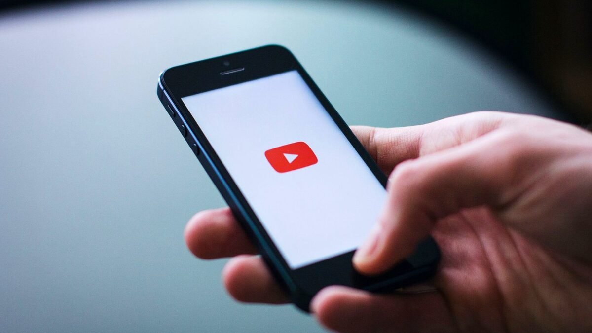 Hand holding a smartphone with the YouTube app open on the screen