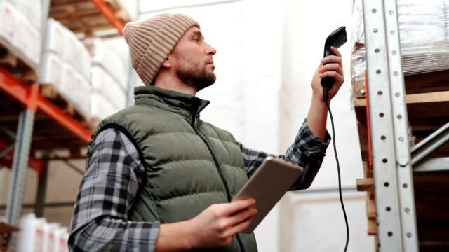 A warehouse worker scans stock with a handheld scanner