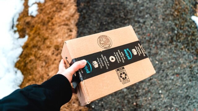 Hands holding a cardboard Amazon Prime parcel