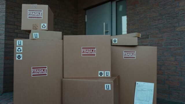 Several cardboard parcels with fragile labels stacked at a building entrance