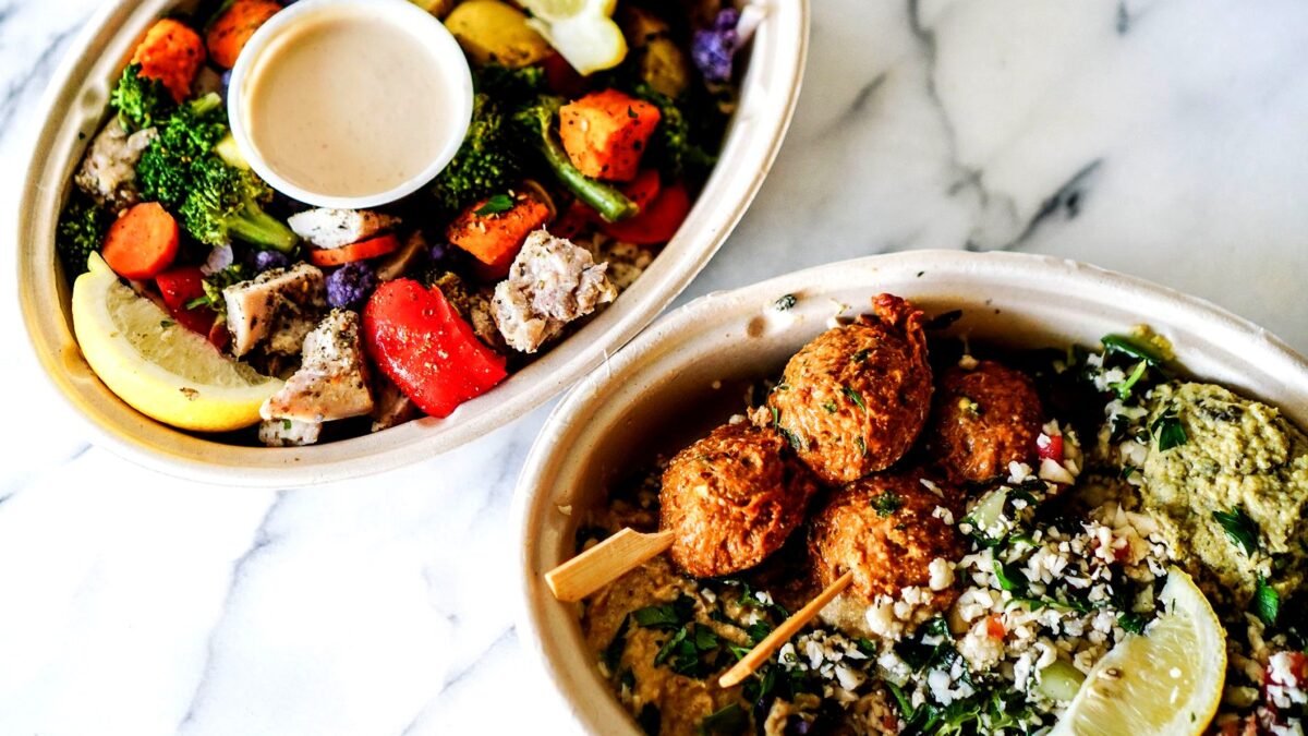 Two Mediterranean bowls with vegetables and grains seen from above