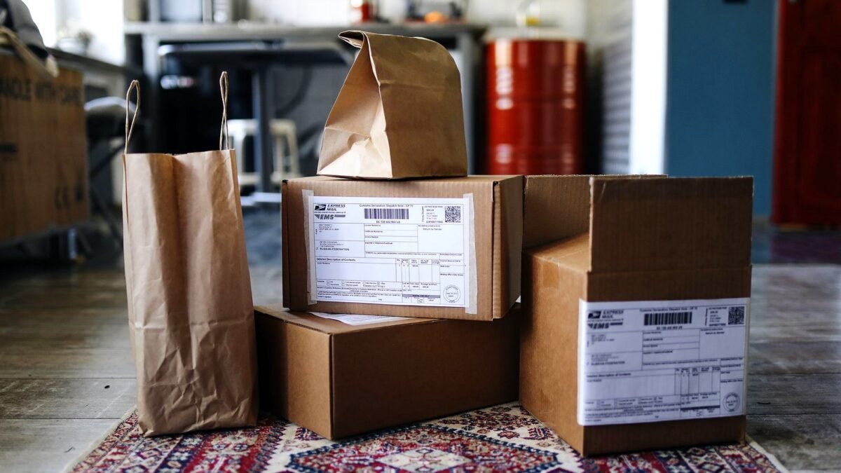 Cardboard boxes and paper shopping bags stacked on a patterned floor