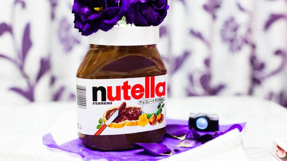 Jar of Nutella hazelnut spread on a table next to purple flowers
