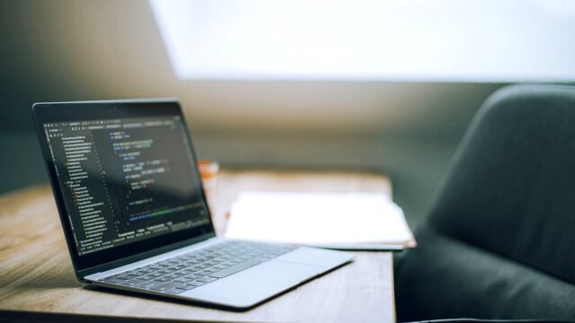 Open laptop showing a code editor on a desk in a bright office