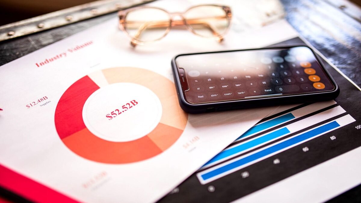 Smartphone lying on printed reports with bar and line charts