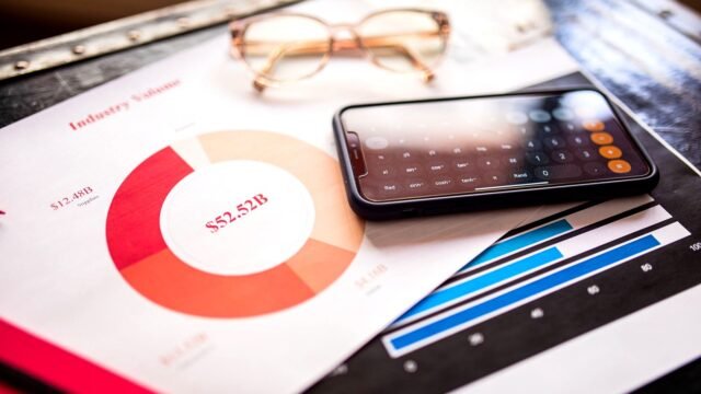 Smartphone lying on printed reports with bar and line charts