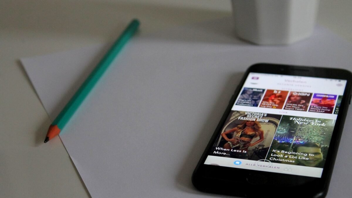 Smartphone showing a news page next to a pencil and notes on a desk