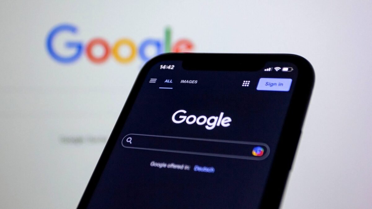 A smartphone screen shows the Google search page in dark mode