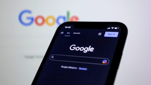 A smartphone screen shows the Google search page in dark mode