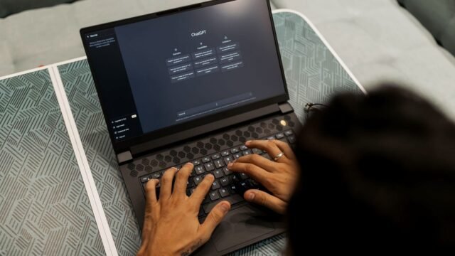 Hands type on a laptop keyboard with the ChatGPT page open on screen