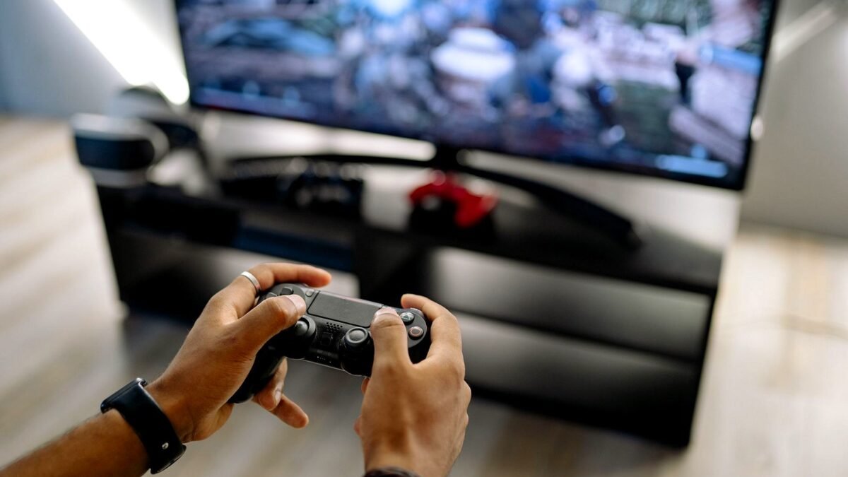 Hands hold a game controller in front of a TV screen during a video game session