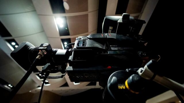 A professional video camera on a tripod in a television studio