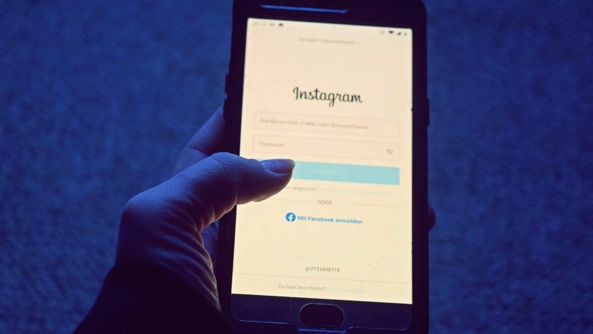 A hand holds a smartphone showing the Instagram login screen