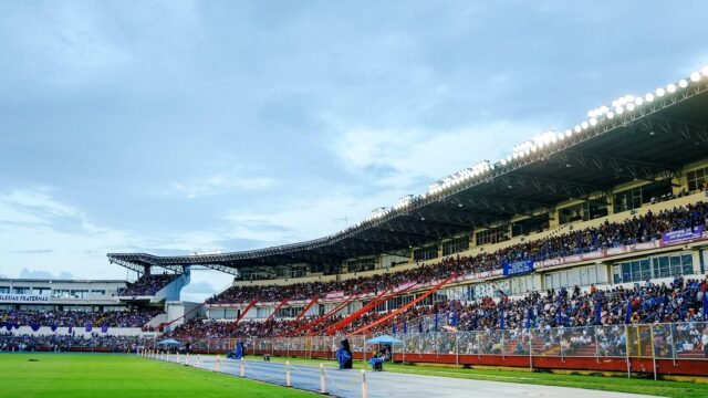 Packed football stadium with spectators watching a match in daylight