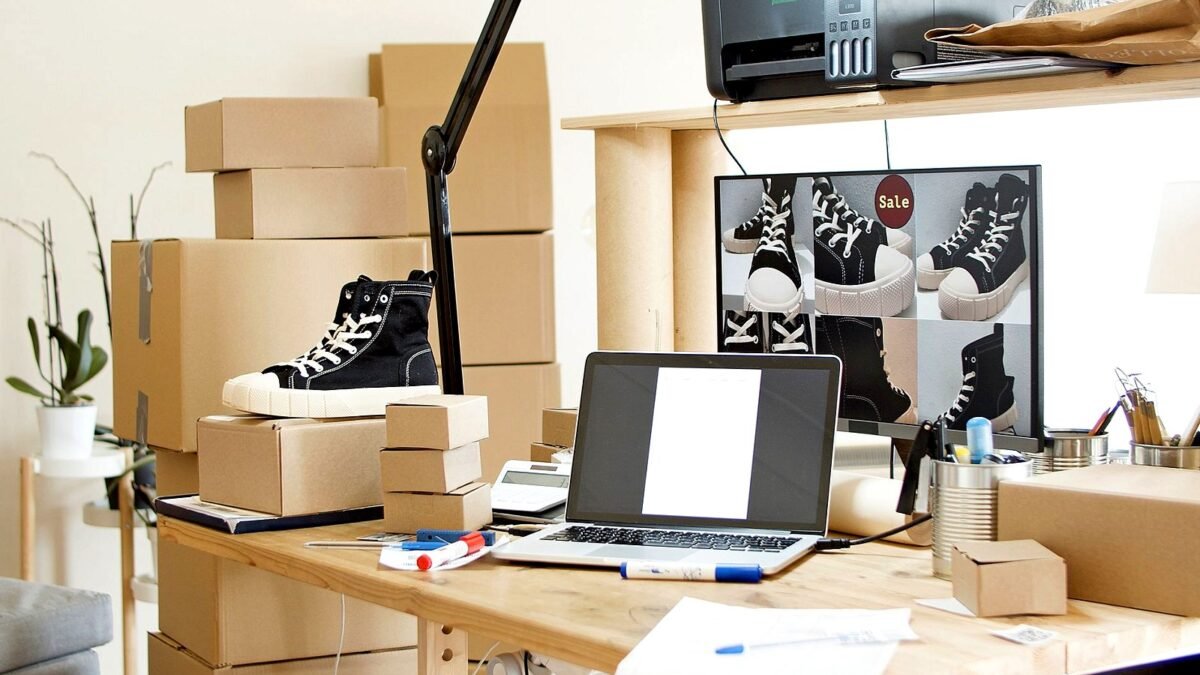Desk with a laptop, shipping boxes and sneakers ready to pack for an online order