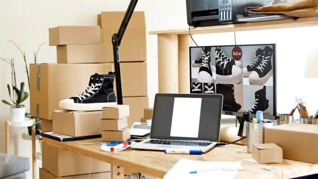 Desk with a laptop, shipping boxes and sneakers ready to pack for an online order
