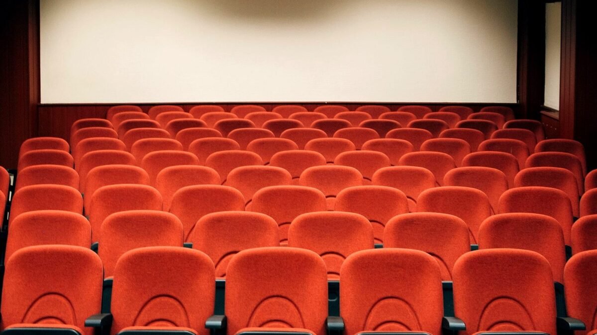 Rows of red seats facing a large screen in a cinema hall