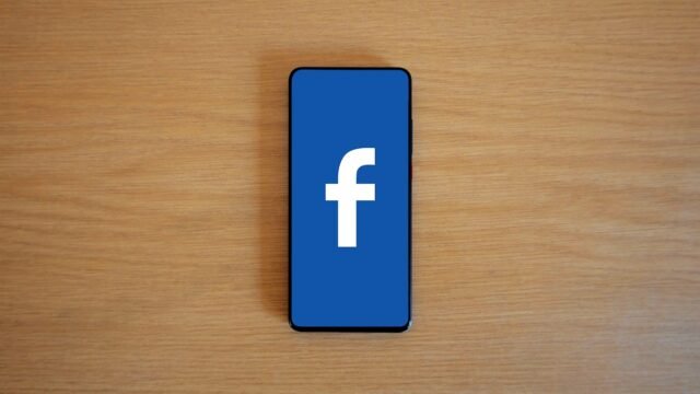 Smartphone with the Facebook logo on its screen lying on a wooden table