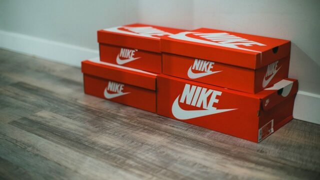 Stack of red Nike shoe boxes on a wooden shop floor