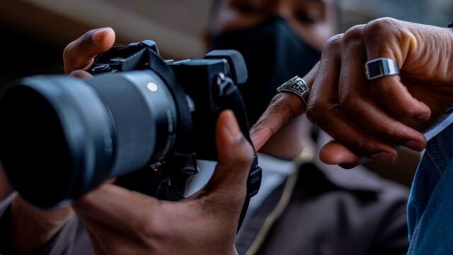 Hands adjusting the settings on a DSLR camera