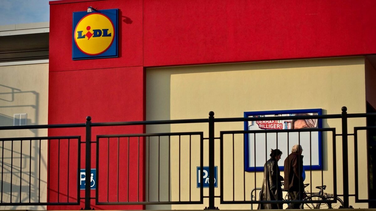 People walking past a Lidl supermarket with the store sign in view