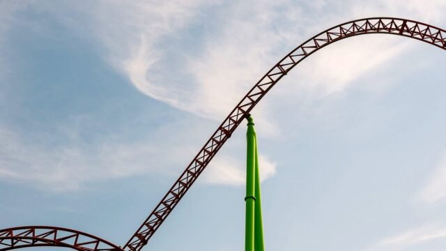 Steel roller coaster track against a clear blue sky
