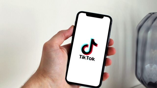 Hand holding a smartphone with the TikTok app open on screen