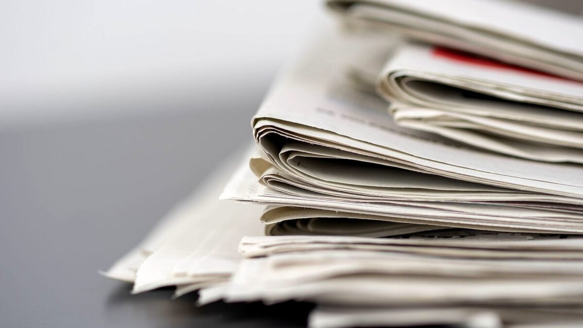 Stack of folded printed newspapers on a table in daylight