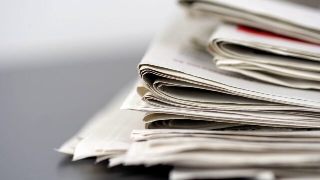 Stack of folded printed newspapers on a table in daylight