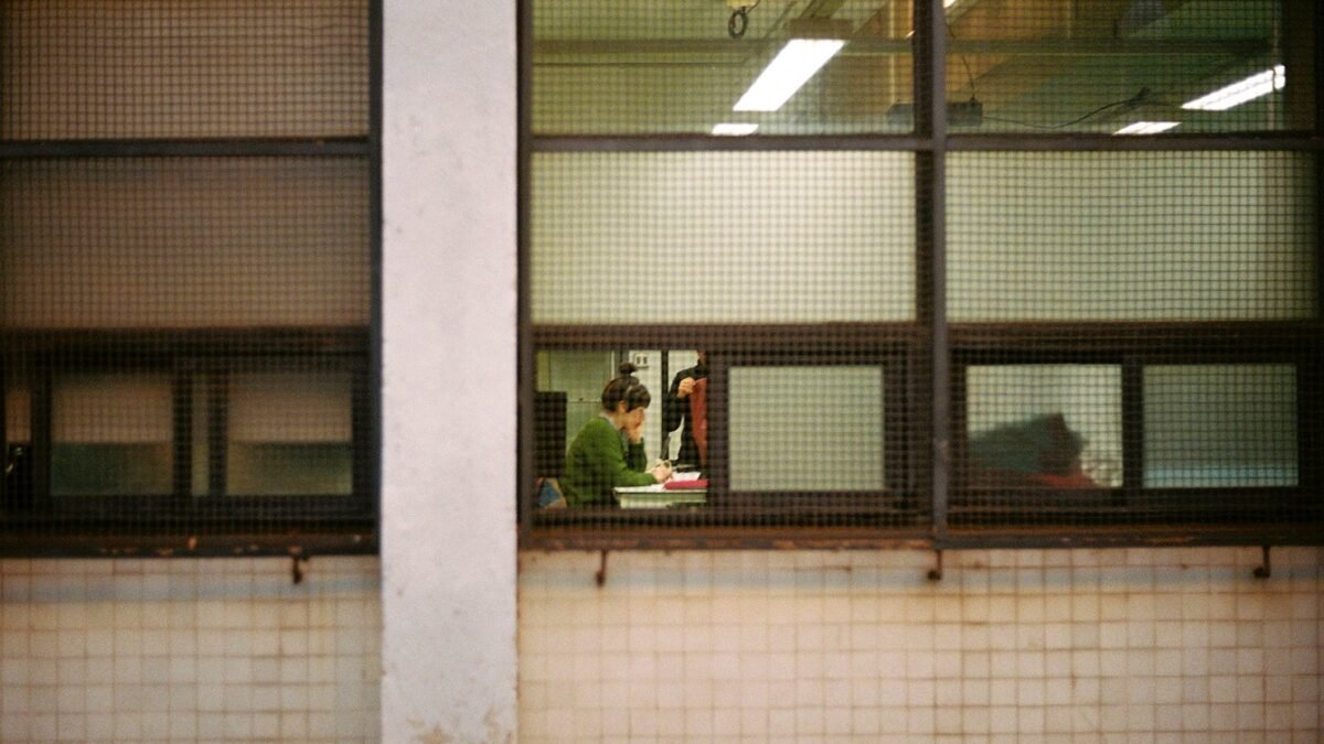 Office workers at their desks seen through a glass wall